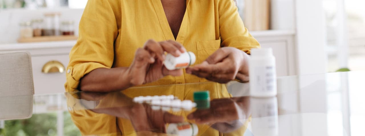 A woman pouring medication tablets into her hand