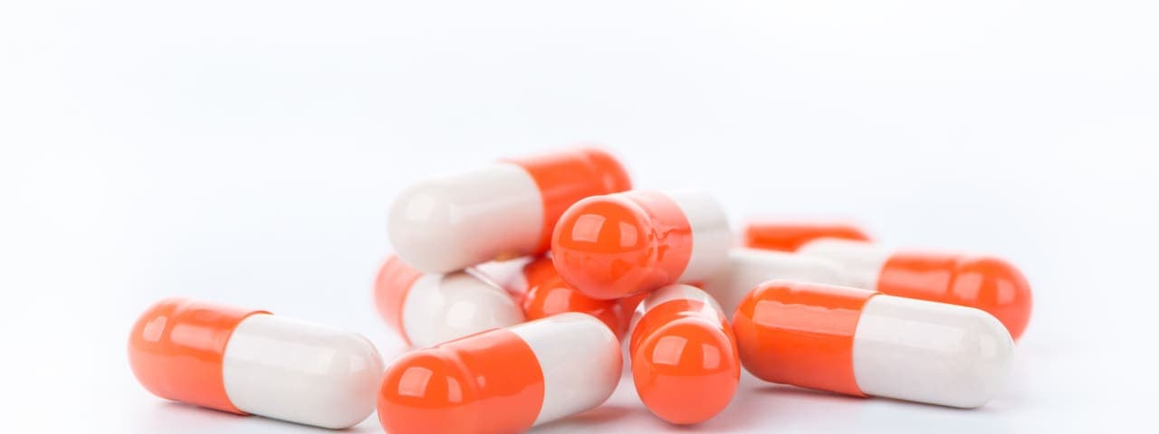 Heap of white orange capsules on white background