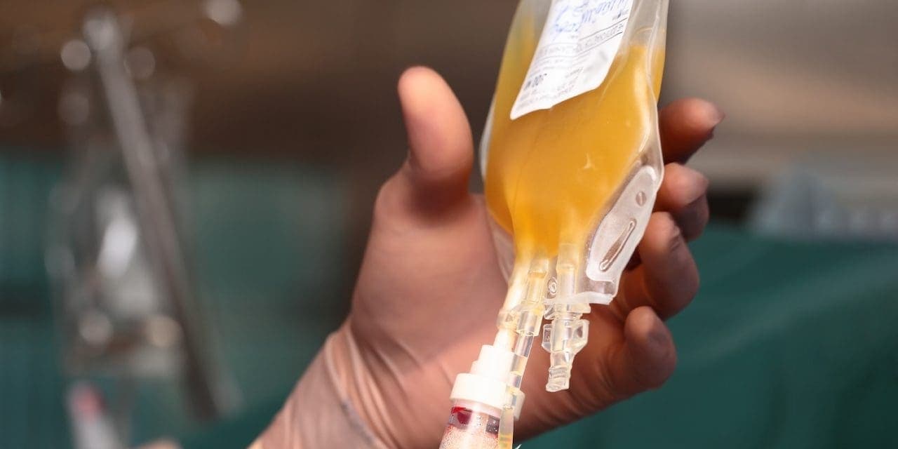 closeup of hand holding a bag of plasma blood dripping